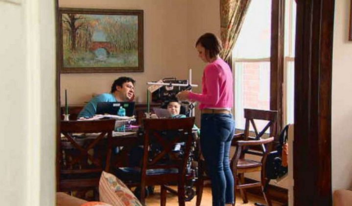 Man, woman and child in a wheelchair around dining room table