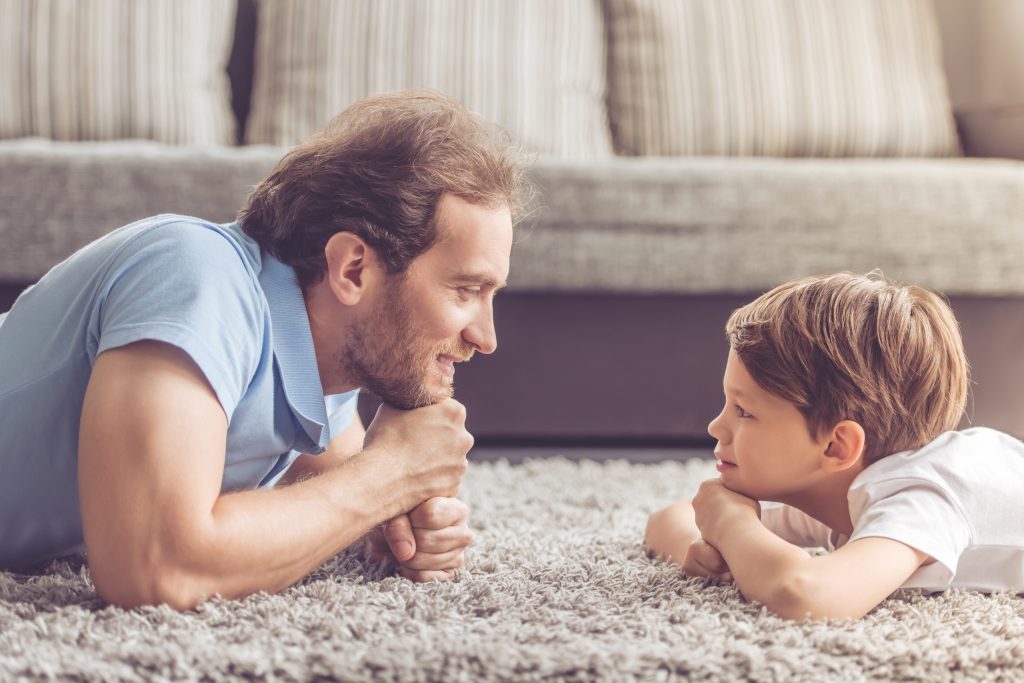 father and son laying on floor watching each other