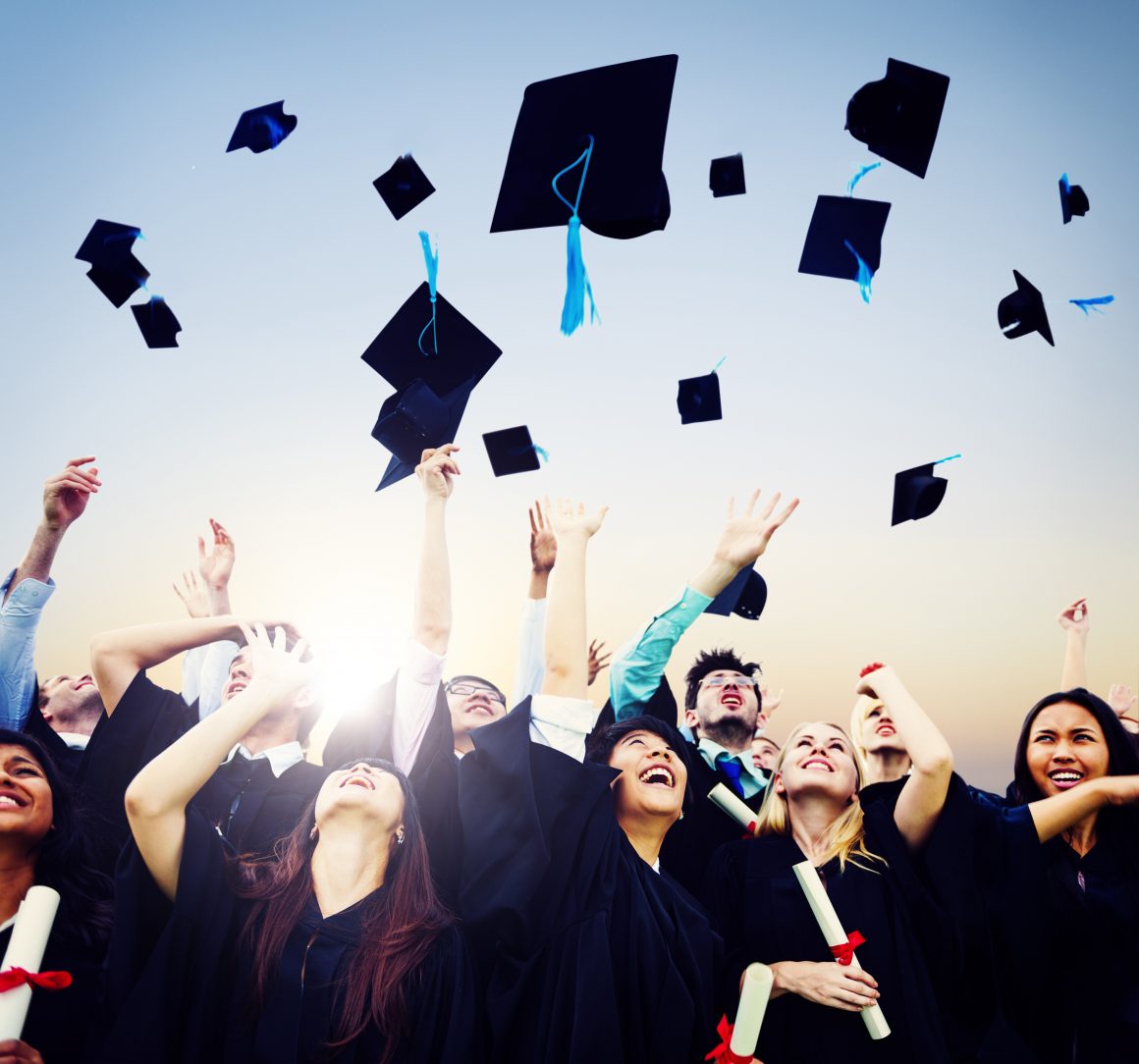 group of graduates throwing caps into the air