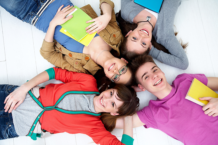 Teenagers holding books laying on the floor